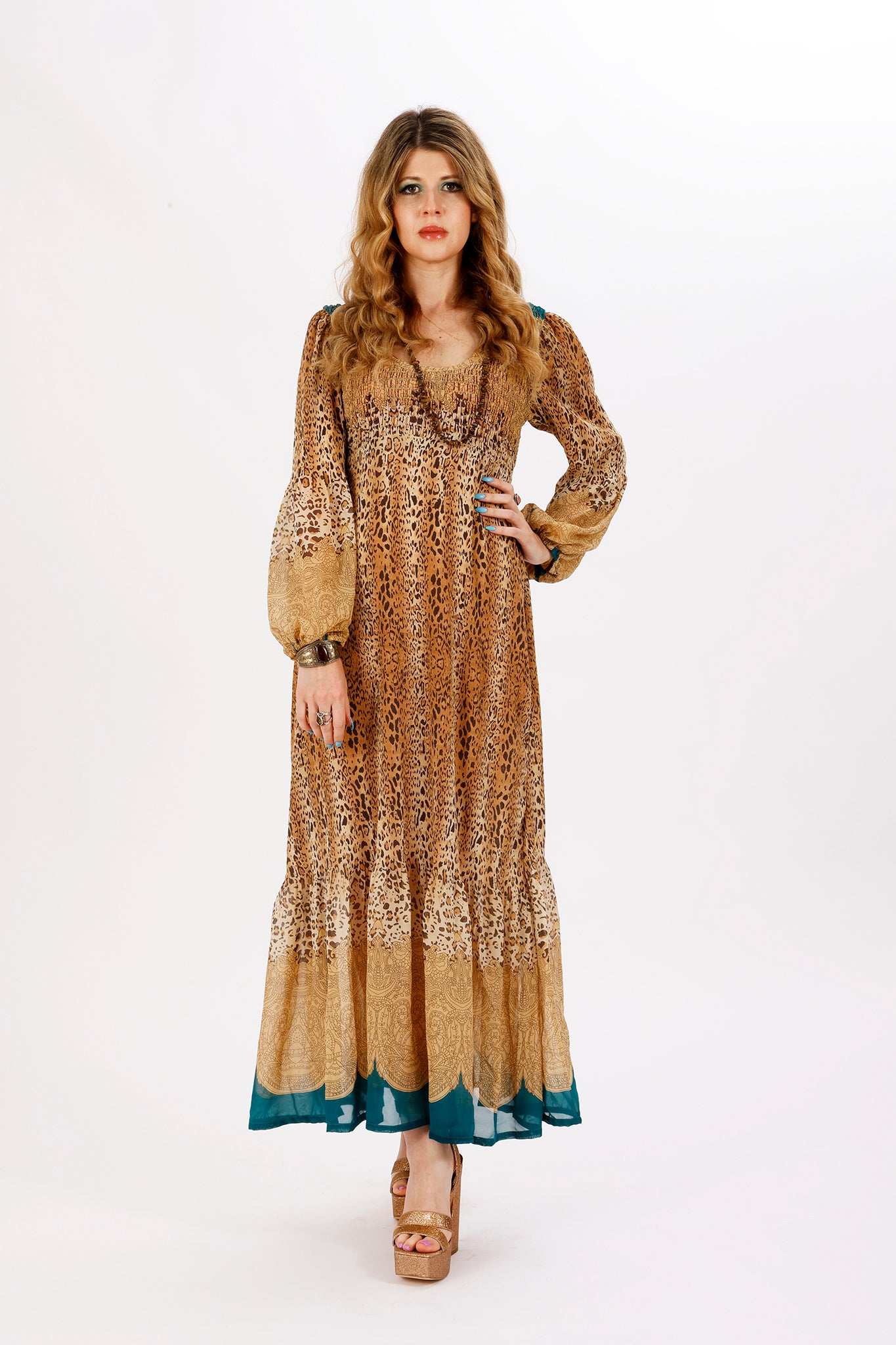 A woman standing and posing in a leopard print maxi dress with balloon puff sleeves and an empire waistline.